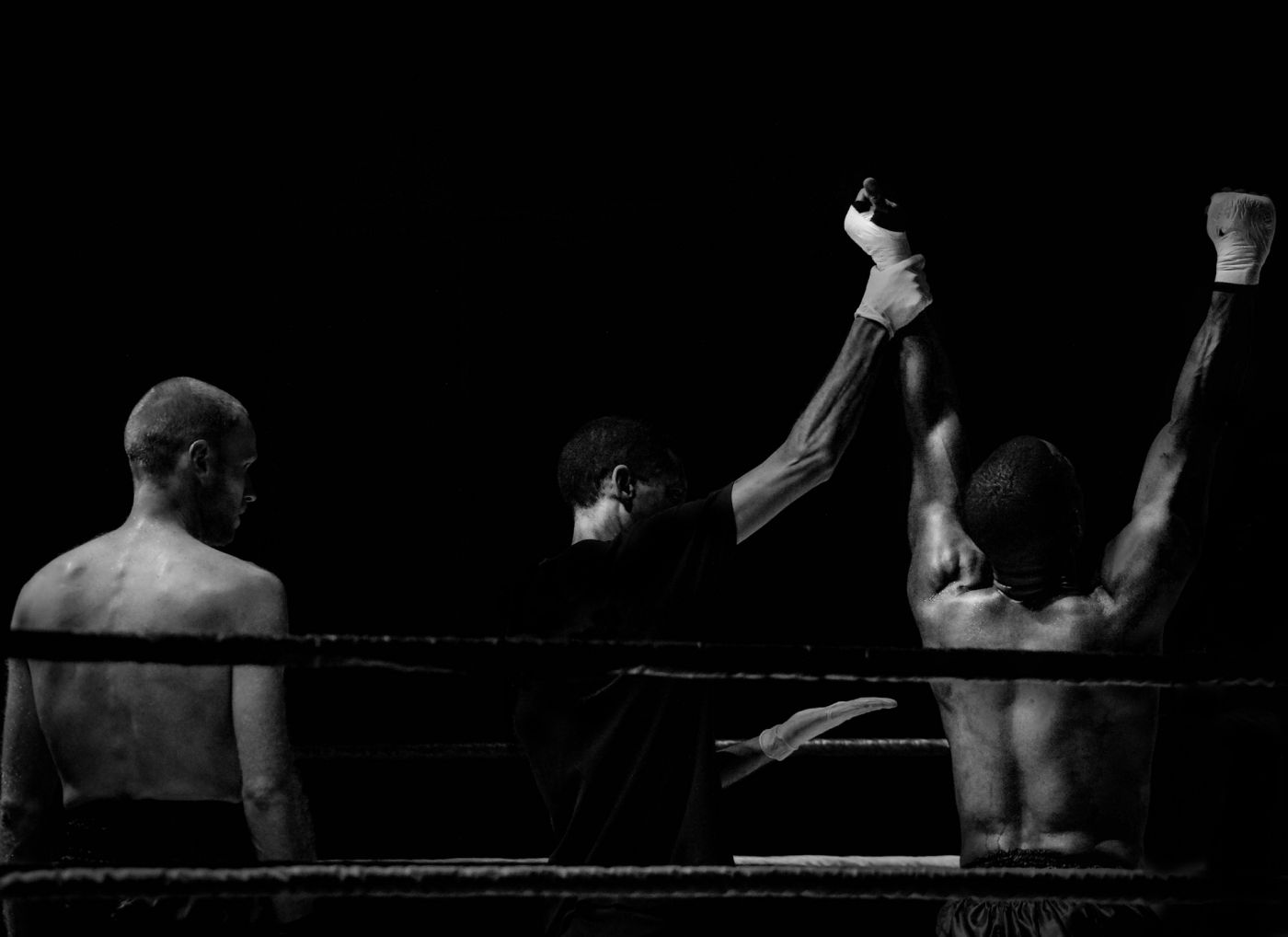 Boxer having arms held aloft after victory in the rink - black and white