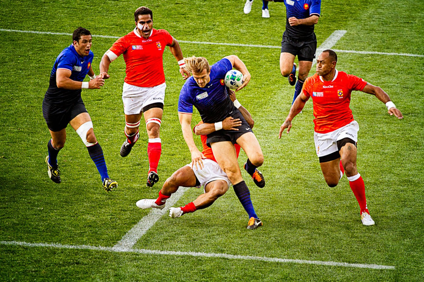 French rugby player being tackled by Tongan player