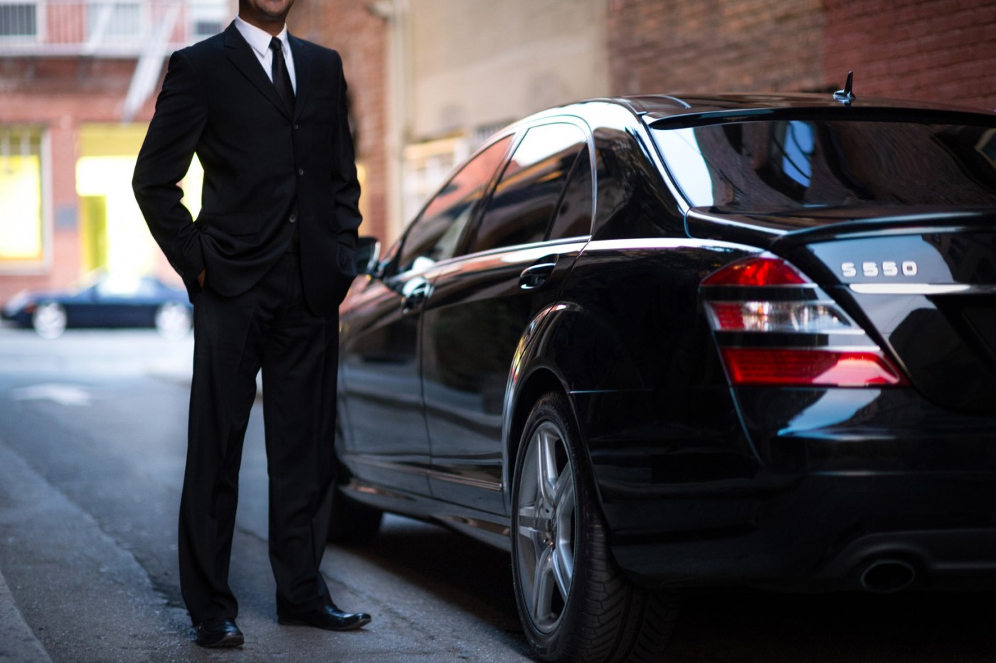 Chauffeur in a suit next to a black car