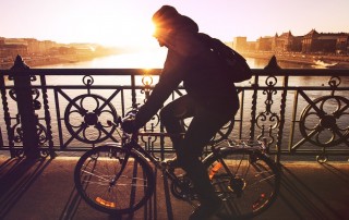 Man on bike at sunset crossing a bridge