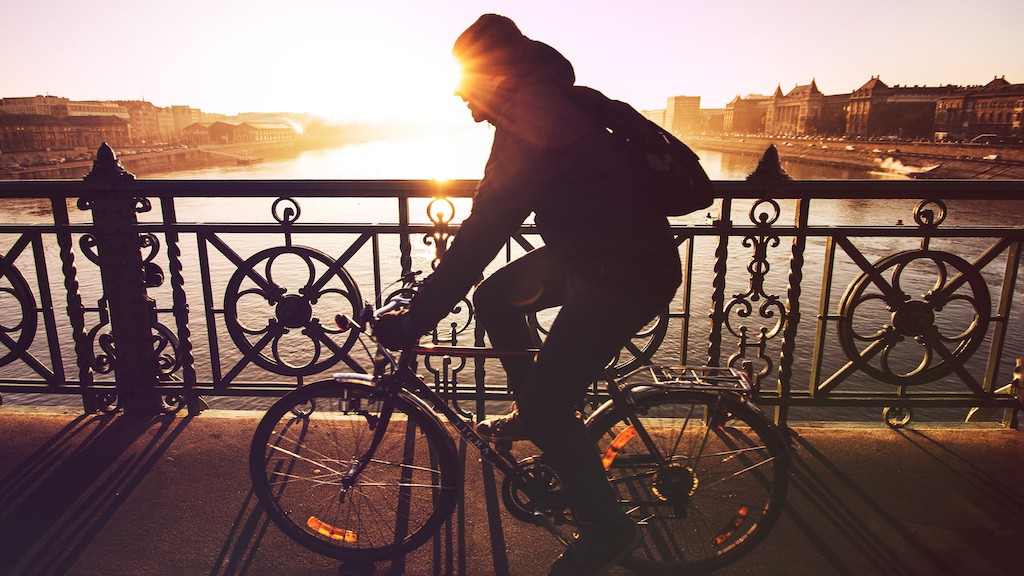 Man on bike at sunset crossing a bridge