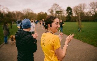 Woman in glasses clapping parkrun participants