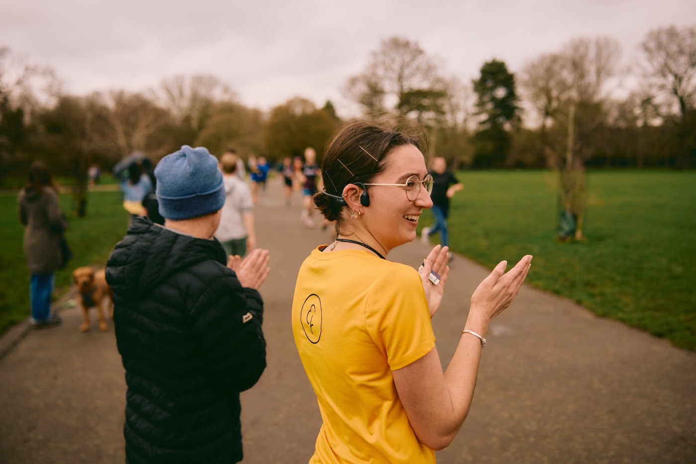 Woman in glasses clapping parkrun participants